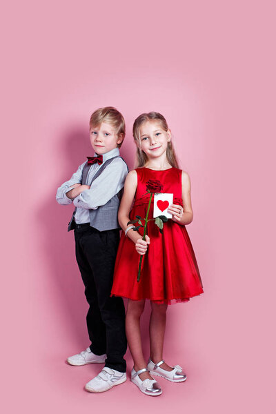 cute six year old girl with a Valentines card in her hand and funny boy on pink background