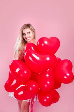 Pembe arka planda kırmızı balonları olan sevgililer günü kızı. Güzel kadın eğleniyor ve sevgililer gününü kutluyor.
