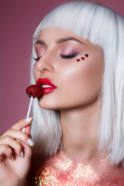 Szépség Glamour modell nő divatos fehér haj stílus és kreatív smink gazdaság piros édes nyalóka cukorka — Stock Fotó