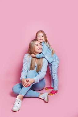 Güzel genç bir kadın ve tatlı küçük kızı sarılıp gülümsüyor. Anneler Günü