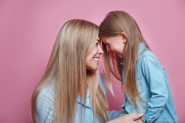 Feliz mamá riéndose acariciando las narices tocando con su linda hija sobre fondo rosa —  Fotos de Stock