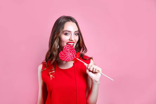 Fashion sweet woman having fun with lollipop over pink background