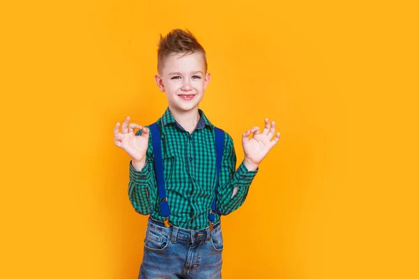 Cute little boy kid showing okay gesture on yellow background — ストック写真