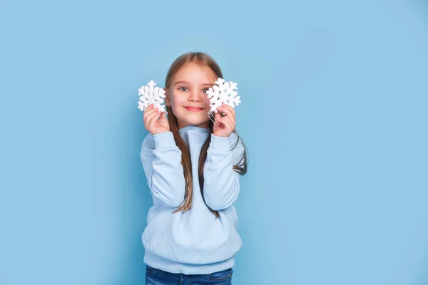 Little girl playing with christmas tree snowflakes on blue background — 스톡 사진