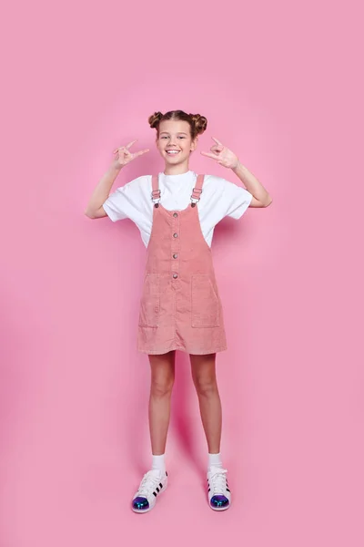 Belle fille en t-shirt blanc, denim rose debout avec des cornes de roche et regardant la caméra — Photo