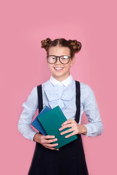 분홍색 배경으로 책을 들고 있는 안경을 쓴 젊은 학생이 웃고 있다 — 스톡 사진