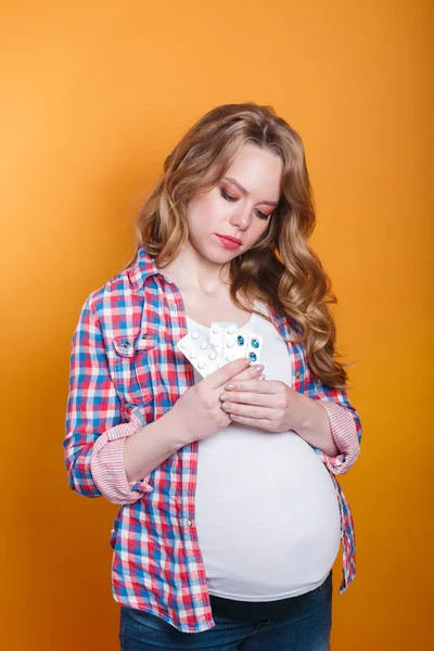 Pregnant woman with pills in hand on yellow background. Medicine during pregnancy — Stockfoto