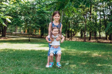 Yaz parkında yeşil çimlerde oynayan iki mutlu çocuk.