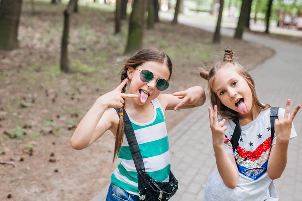 Δύο κομψά κοριτσάκια με γυαλιά ηλίου που διασκεδάζουν σε υπαίθριο χώρο — Φωτογραφία Αρχείου