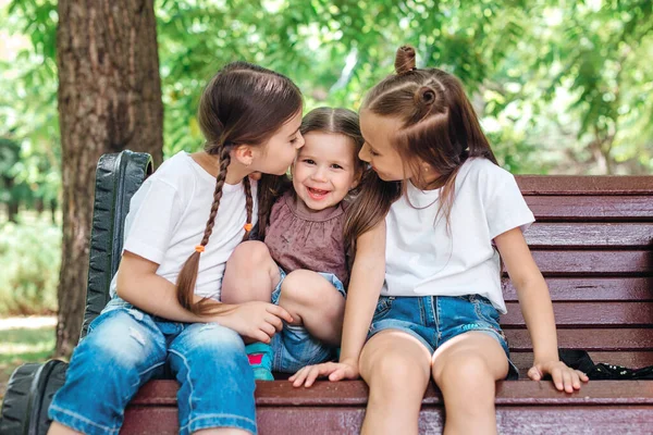 Tres hermanas sonriendo y abrazándose al aire libre en el parque de verano . — Foto de Stock