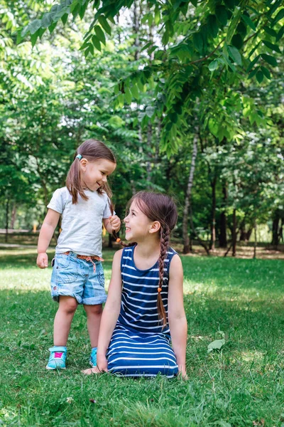 Dos hermanas felices jugando en la hierba verde al aire libre en el parque de verano — Foto de Stock