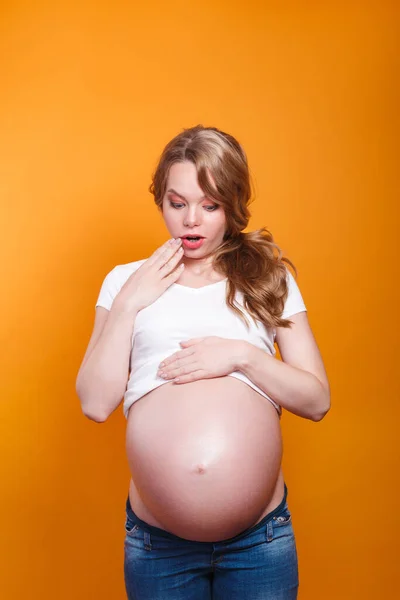 Foto av förvånad känslomässig gravid kvinna står över gul bakgrund. — Stockfoto