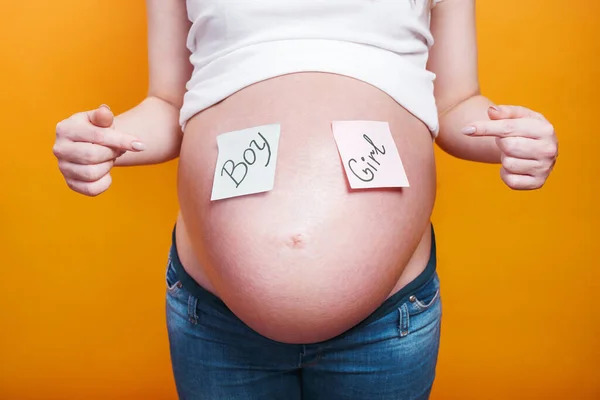 Zwangere vrouw met papieren stickers op buik op gele achtergrond, — Stockfoto