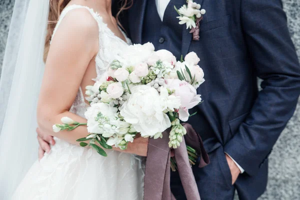 Bruden håller en bukett blommor i hennes hand, brudgummen omfamna henne — ストック写真