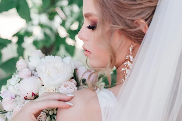 Primer plano de la novia hermosa con flores de la boda ramo en el parque. Novia con maquillaje de boda y peinado . — Foto de Stock