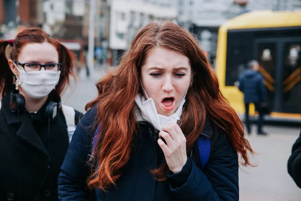 Donna soffrono di malati e indossando maschera facciale. Donna europea in maschera protettiva sentirsi male per strada in città — Foto Stock