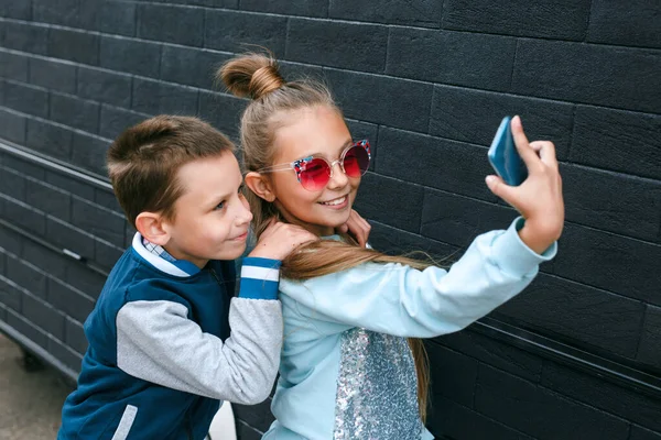 Cute boy and pretty little girl in sunglasses making a selfie using a smart phone