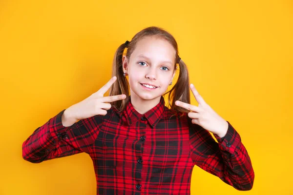 Stylová holčička ukazuje mír znamení na žlutém pozadí — Stock fotografie
