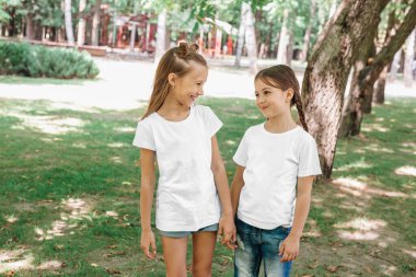 Dışarıdaki parkta duran beyaz tişörtlü iki küçük kız. Model.