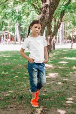 Parkta poz veren beyaz gömlekli küçük kız.