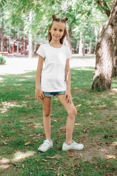 Retrato de una niña feliz con una camiseta blanca en el parque — Foto de Stock