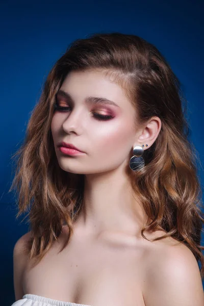 LΌμορφη γυναίκα μοντέλο με σγουρά χτένισμα και το βράδυ make-up κοιτάζοντας πλάγια στο μπλε φόντο — Φωτογραφία Αρχείου