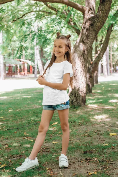 Retrato de una niña feliz con una camiseta blanca en el parque — Foto de Stock