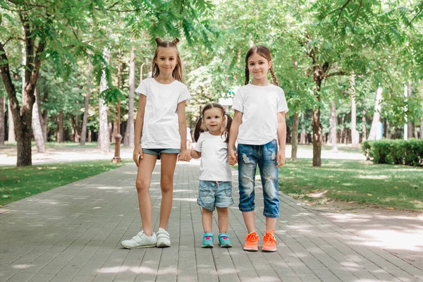 Los niños del árbol con camisetas blancas están de pie tomados de la mano en el parque. Prepárate. . — Foto de Stock