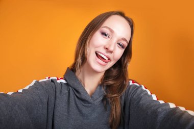 Sarı stüdyo arka planında selfie çeken komik genç bir kadın.