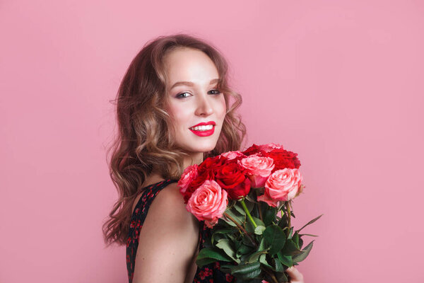 Portrait of a very beautiful sensual and sexy girl with flowers on pink studio background