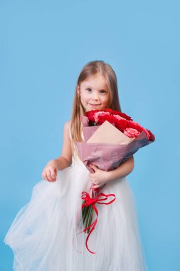 Anneler gününde mavi arka planda annesine çiçek veren küçük bir kız.