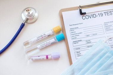 Coronavirus kan testi konsepti. Tıbbi form Coronavirus testi, solunum maskesi, beyaz arka planda stetoskop olan laboratuvar masası.
