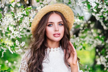 Bahar çiçekli bahçede şehvetli genç bir kadının yakın plan portresi.