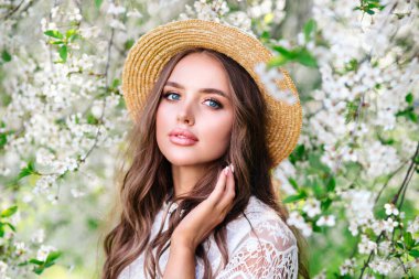 Güneşli bahar çiçekli bahçede şehvetli genç bir kadının yakın plan portresi.