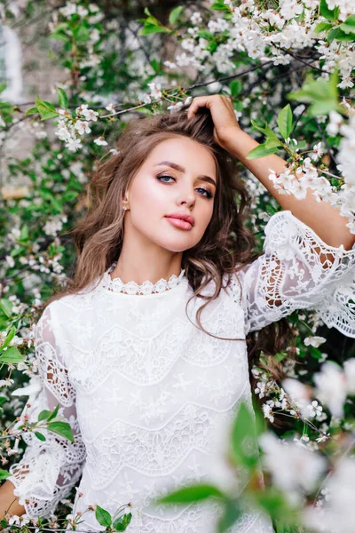 Baharda elma bahçesinde poz veren güzel genç bir kadın.