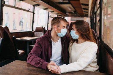 Otobüste genç bir çift, birlikte seyahat ediyorlar, virüsü önlemek için hijyenik maske takıyorlar.