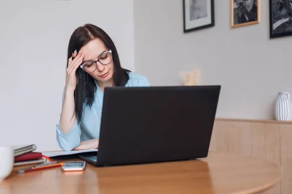 Frustrated business woman worried about problem sitting with laptop at home