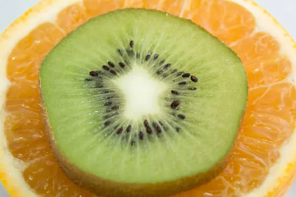 round slice of kiwi on a slice of orange close up