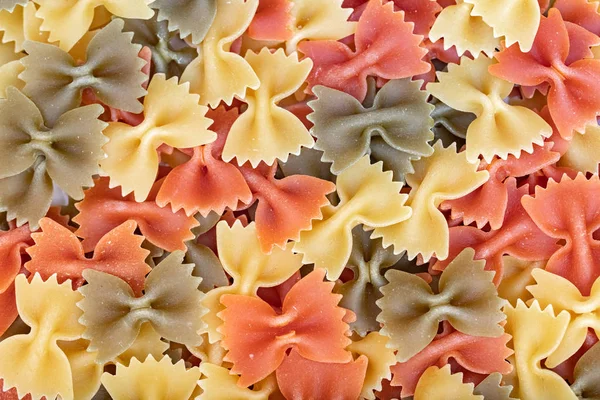 Разноцветное Итальянское Сырье Pasta Farfalle Разливается Больших Количествах Фон Закрывай — стоковое фото