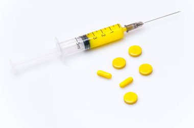 Sarı solüsyonlu tıbbi bir şırınga beyaz bir arka planda yatıyor.