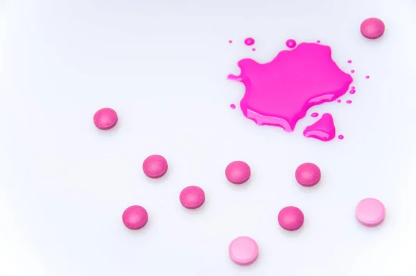 Mor çözeltisi olan tıbbi bir şırınga haplarla çevrili beyaz bir arka planda yatıyor.