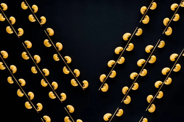 Siyah bir arka planda mücevher kolyesi şeklindeki kaliteli makarna.