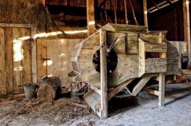 Old wooden threshing machine standing in an old barn clipart