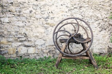 Eski ahşap taş duvar önünde çimenlerin üzerinde duran kesici saman