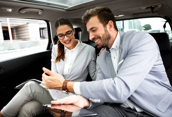 business people working on tablet in a car