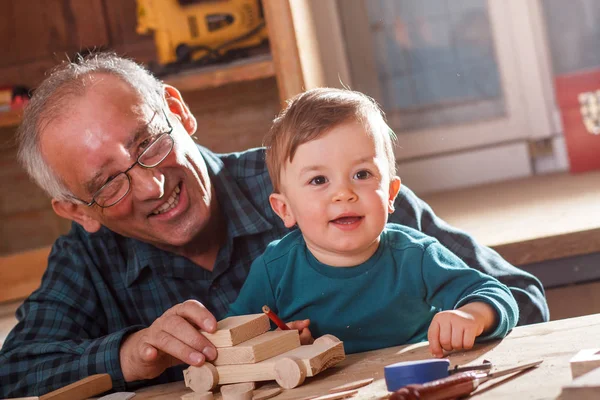 elderly grandfather carpenter teaching little grandson working in manufactory, woodwork concept