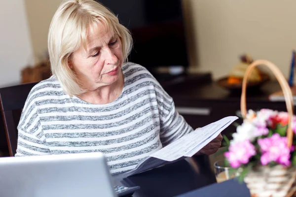 senior woman reading documents at home