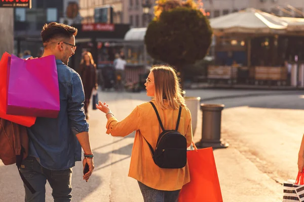 Young couple walking in city with shopping bags