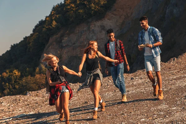 Group of four friends hiking through countryside together at sunset.