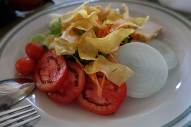 Beyaz tabakta Müslüman salatası, bir sürü sebzeli lezzetli aperatif, kırmızı domates, yeşil yaprak, soğan, haşlanmış yumurta, tofu, yüksek beslenme.